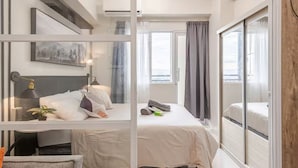 Una camera d'hotel moderna con un letto grande, una scrivania con una lampada, una piccola pianta e un quadro appeso al muro.