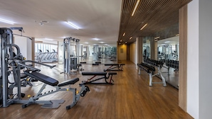 Una palestra con diverse attrezzature per l'allenamento, pavimento in legno e specchi alle pareti.