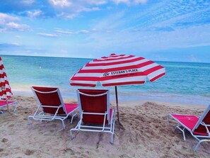 A beach with red and white striped umbrellas and red lounge chairs. - Wonderful Views at Lyfe Resort @rent4us (Hollywood)