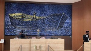 A reception desk with a large painting of a boat on water behind it.