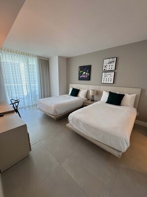 A modern hotel room with two single beds, a desk, and a chair.
