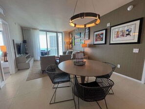A modern living room with a round dining table, black wicker chairs, a sofa, and a TV. - Wonderful Views at Lyfe Resort @rent4us (Hollywood)
