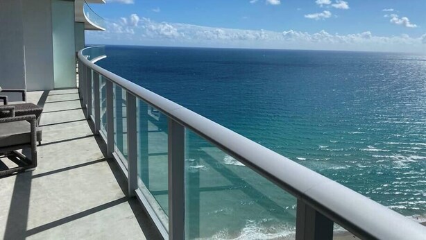 A balcony with a glass railing overlooking the ocean. - Wonderful Views at Lyfe Resort @rent4us (Hollywood)