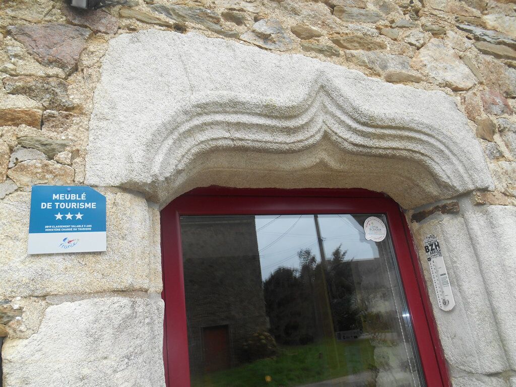 A stone building entrance with a red door and a sign indicating it is a tourist attraction.