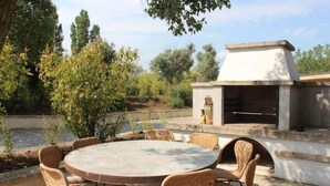An outdoor dining area with wicker chairs and a round table, a barbecue grill, and a view of a body of water. - Casa Kathy (Pertuis)