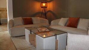 A modern living room with a glass coffee table, a sofa, and a floor lamp.