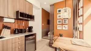 Een moderne keuken met houten kastjes, een inbouwoven en een eethoek met een houten tafel en stoelen.