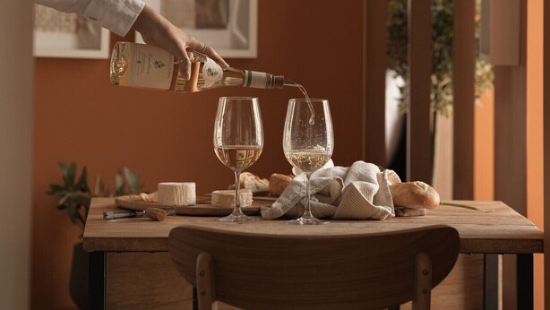 Een eettafel met twee wijnglazen, een fles wijn en een brood.