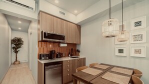 A modern kitchen with wooden cabinets, a built-in microwave, and a dishwasher. There is a dining table with four chairs and a hanging light fixture. - Loft Folk 103 Downtown Quebec City (Québec City)