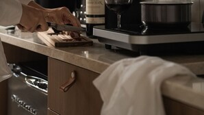 Una cocina con estufa, una botella de vino y una copa de vino sobre la encimera.