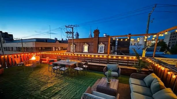 Een terras buiten met zitplaatsen, een tafel en lichtjes.