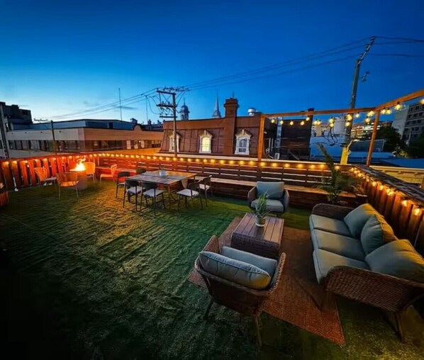 An outdoor patio with seating, a table, and string lights.