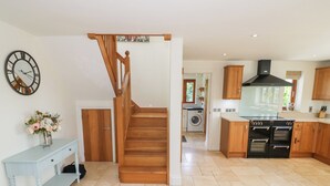 Une cuisine spacieuse avec des meubles de rangement en bois, un four encastré et une grande fenêtre.