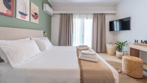 A hotel room with a bed, a TV, a plant, and artwork on the wall. - Residence City Luna, Apartment (Rodos)