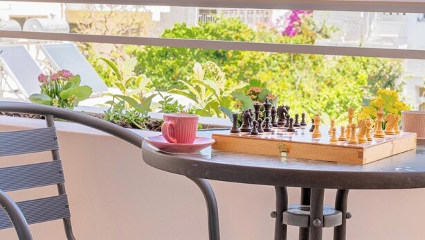 A balcony with a chessboard, a chair, and a table. - Residence City Luna, Apartment (Rodos)