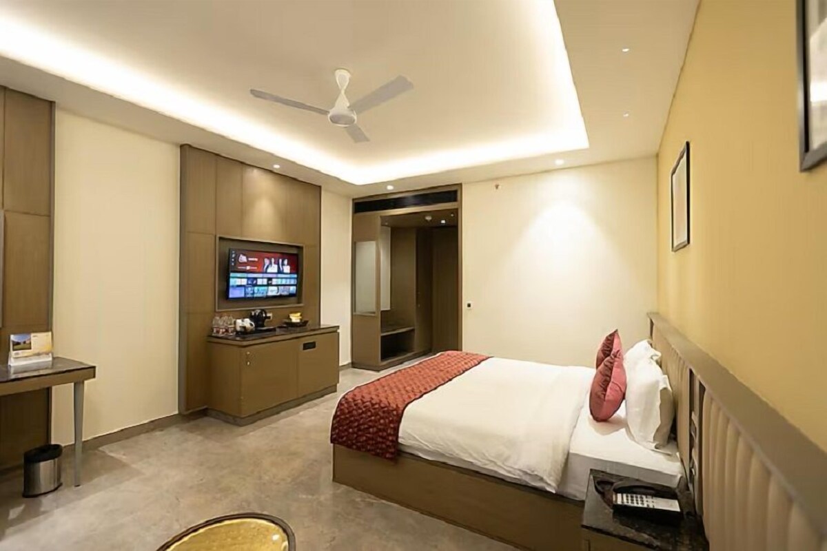 Une chambre d’hôtel équipée d’un lit, d’un bureau, d’une télévision, d’un ventilateur de plafond et d’une armoire.