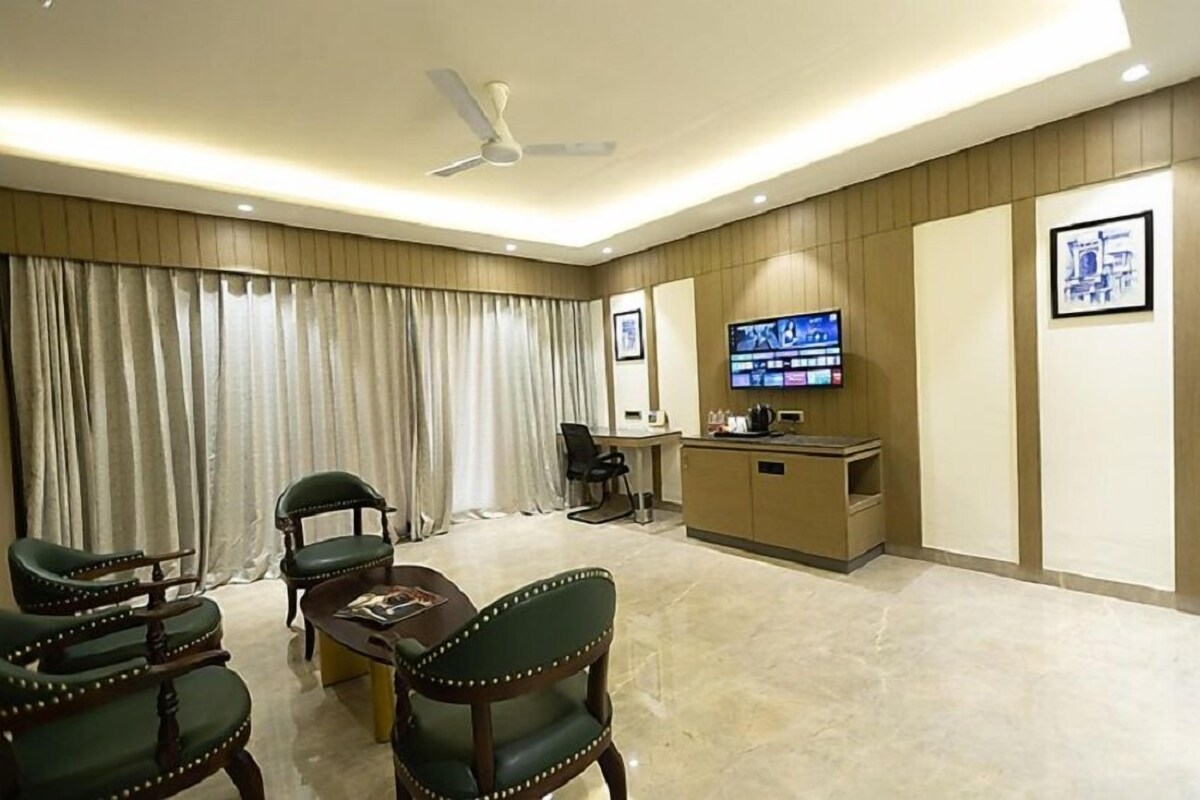 A hotel room with a dining area, a reception desk, a television, and a ceiling fan.