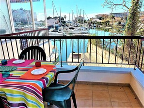 Ein Balkon mit einem für zwei Personen gedecktem Tisch, mit Blick auf einen Yachthafen, Boote und eine freie Wasserfläche.