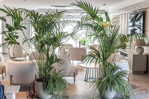 A modern interior with multiple seating areas, large potted plants, and a contemporary design aesthetic. - SH Jávea (Jávea)
