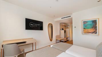 Una habitación de hotel con una cama, un escritorio, una silla, un televisor, un espejo y un cuadro.