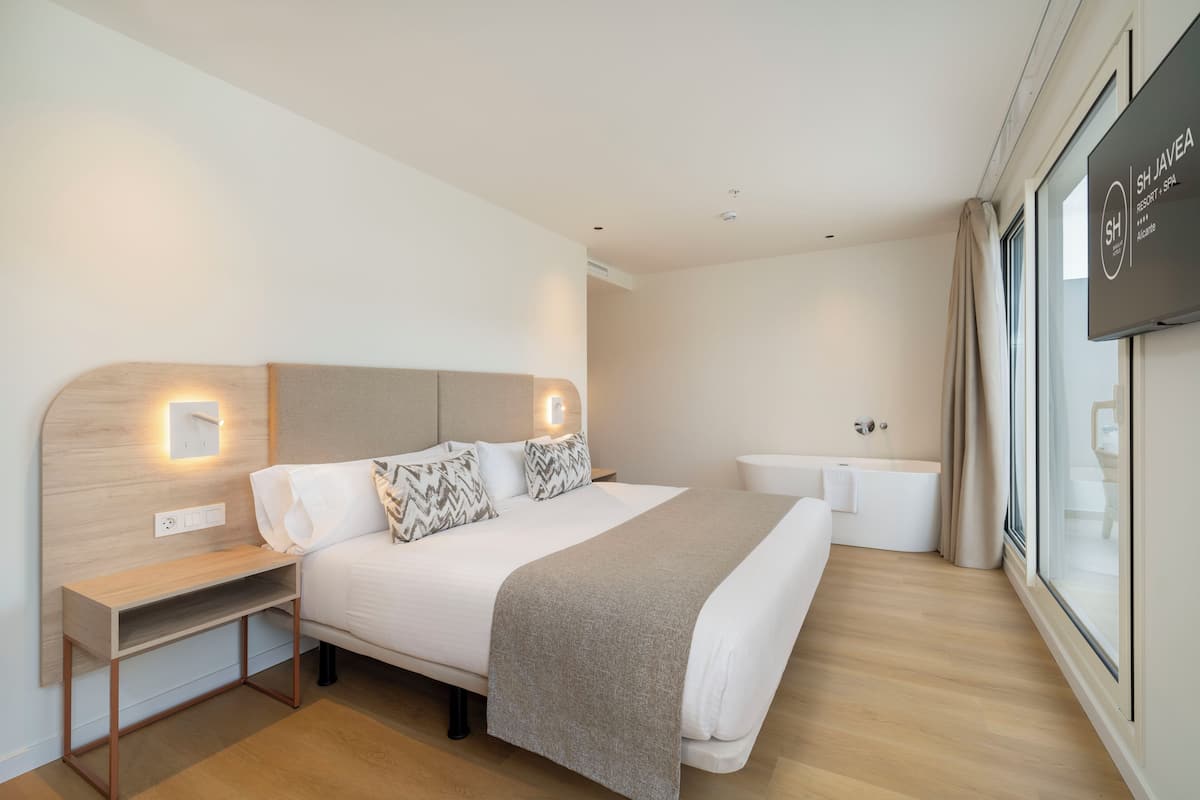 Ein modernes Hotelzimmer mit Bett, Nachttisch und einem fenster mit Vorhängen.