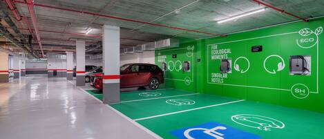 A parking garage with green walls, a red car, and a blue handicapped parking sign.
