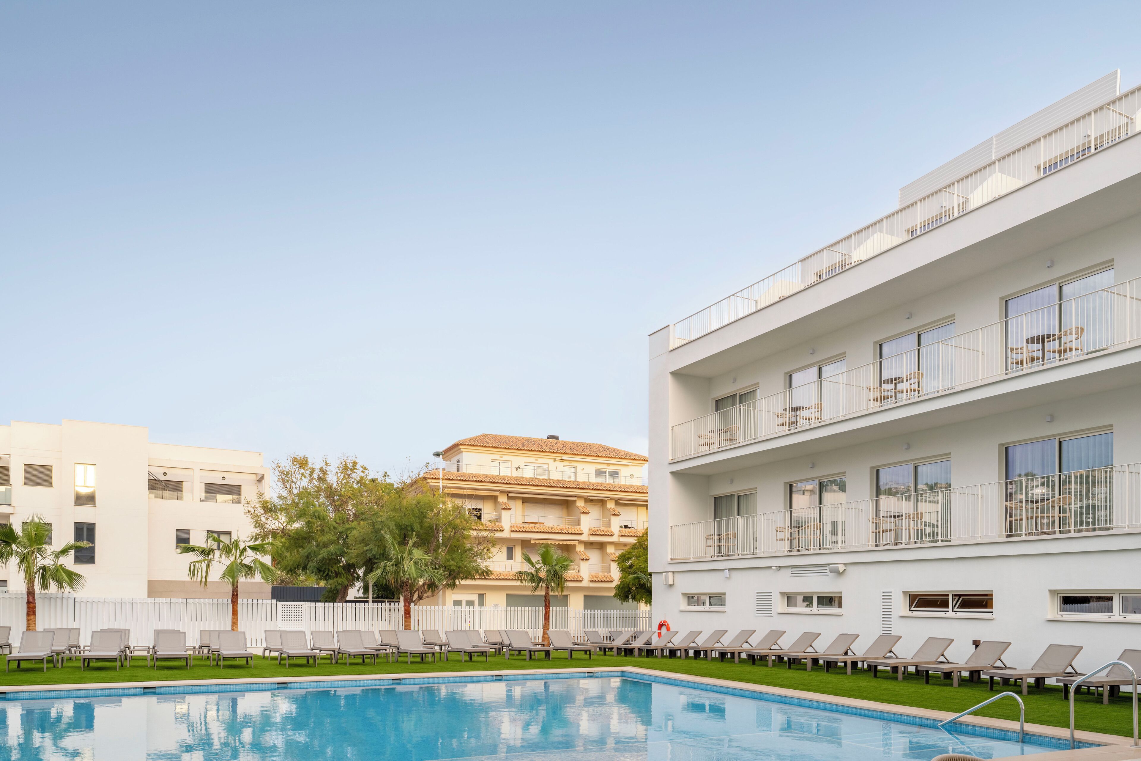 Un espace piscine avec des chaises longues et un bâtiment doté de balcons.