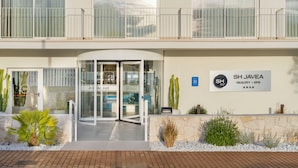 A hotel entrance with a glass door, a sign reading 'SH JÁVEA RESORT + SPA', and a balcony with a railing. - SH Jávea (Jávea)
