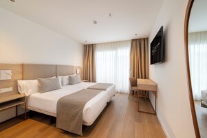 Una camera d'albergo con un letto grande, una scrivania e una TV a parete.