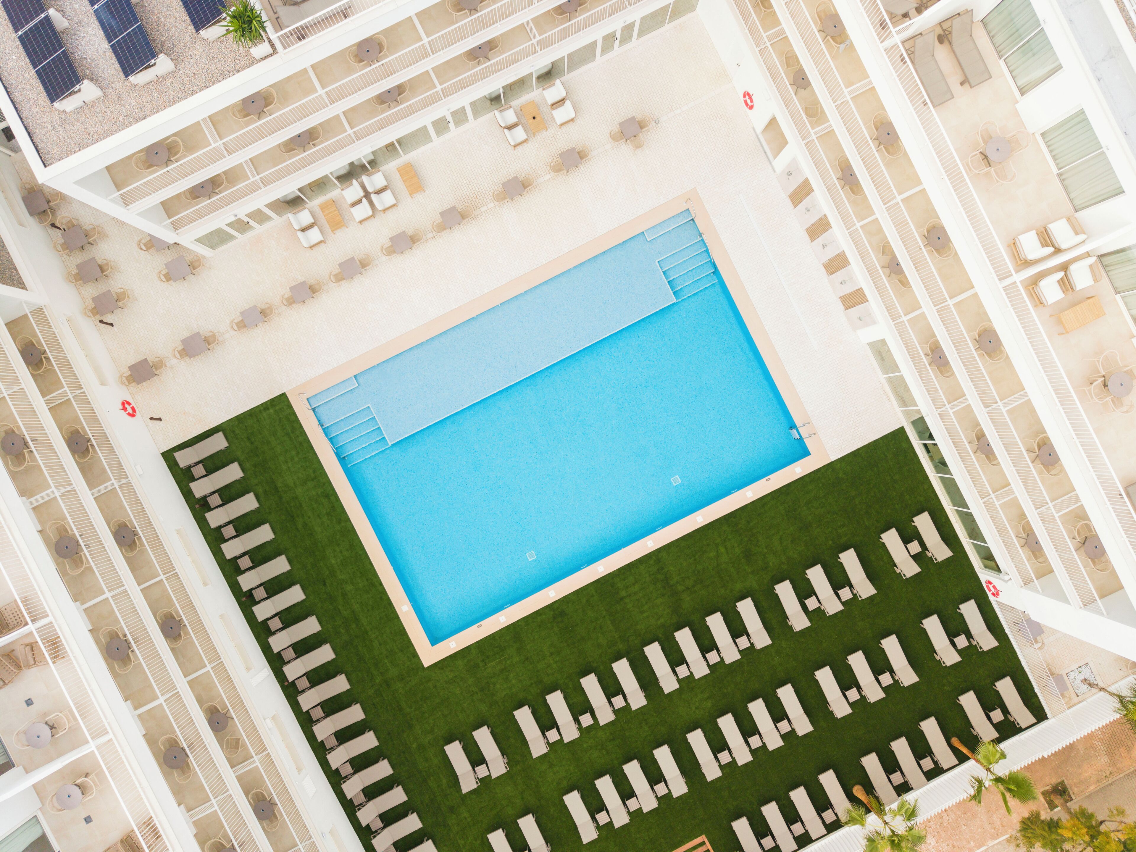 Una piscina al aire libre, sombrillas, sillones reclinables de piscina