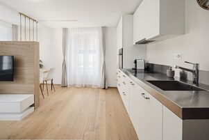 Una cocina moderna con armarios blancos, una encimera de acero inoxidable y un horno empotrado.
