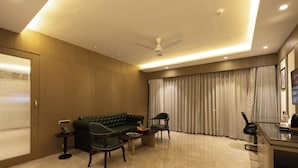 Un salon moderne avec un canapé vert, une table basse, une table d’appoint avec un téléphone et un bureau avec une chaise.