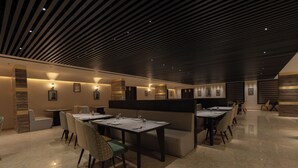 Un restaurant moderne doté d’un plafond élégant et sombre et d’un sol en marbre. Les tables sont disposées dans un espace aéré, avec des sièges confortables.