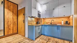 Una cocina moderna con armarios de madera, horno empotrado y un lavamanos.
