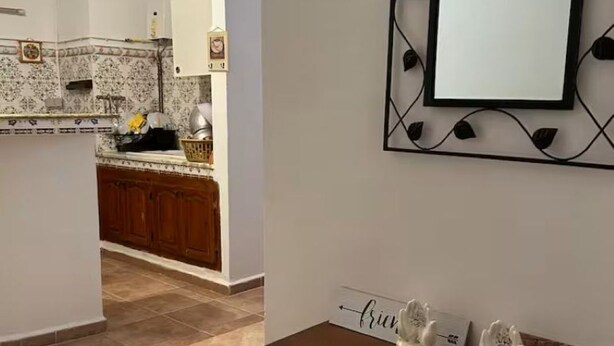 A modern kitchen with a central island, a decorative mirror, and a welcome sign. - APARTMENT IN A QUIET RESIDENCE (Aïn El Turk)