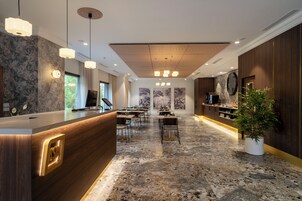 A modern hotel lobby with a reception desk, seating area, and artwork on the walls.
