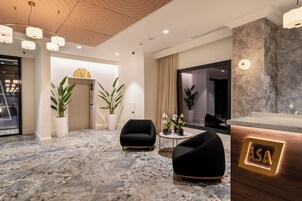A modern lobby with a marble floor, black armchairs, a reception desk with 'ASA' illuminated, and a clock on the wall.