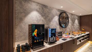 Una cocina moderna con estación de café, un reloj grande y encimera de mármol.