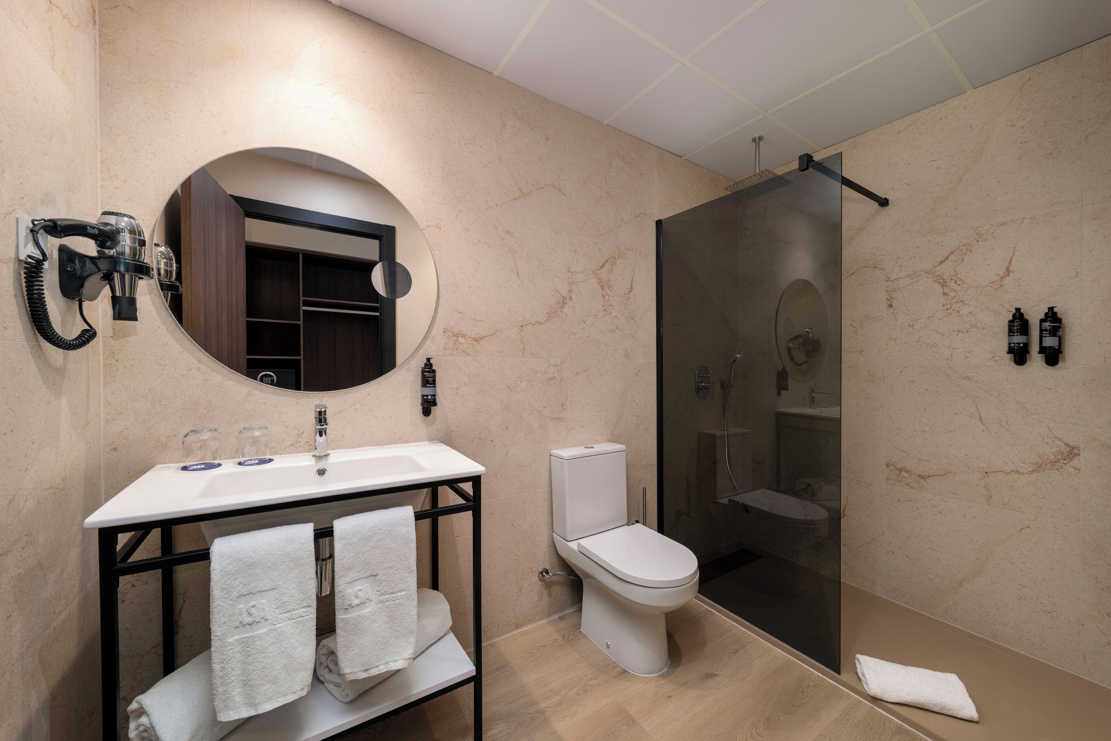 A modern bathroom with a white sink, a toilet, and a glass-enclosed shower.