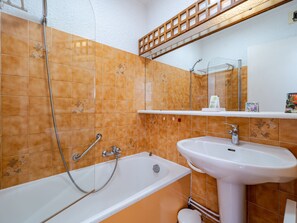 Une salle de bain avec une baignoire, un lavabo et un miroir.