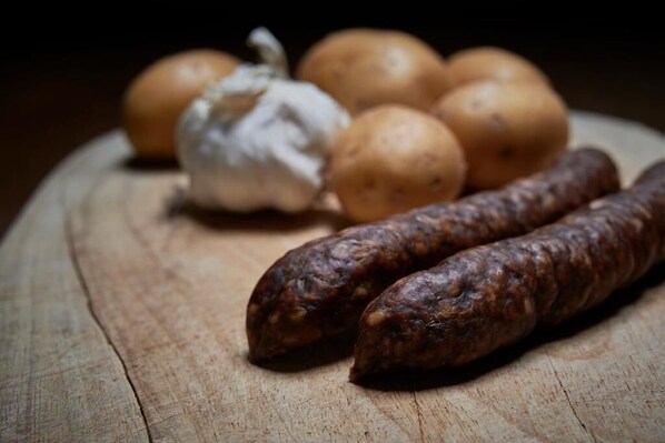 Sausages, garlic, and potatoes on a wooden surface.
