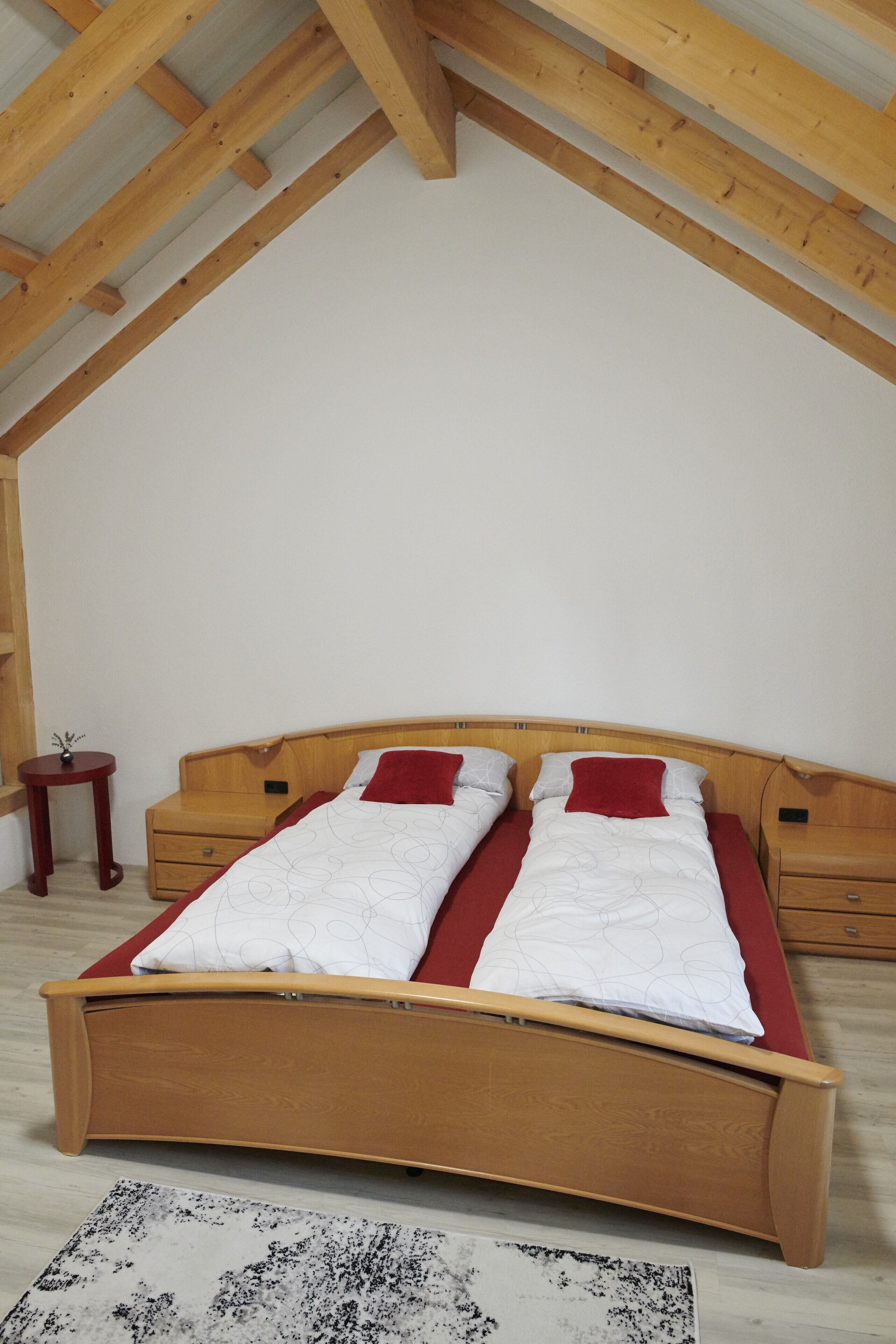 A bedroom with a wooden bed, two bedside tables, and a small nightstand.