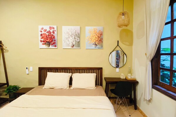 A hotel room with a large bed, a bedside table with a lamp, and three wall-mounted paintings of flowers. - PIA homestay - Tours & Motorbike rentals (Thuc Phan)