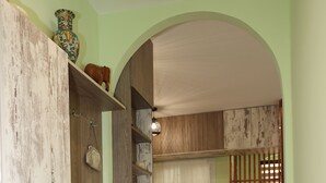 Eine schmale Küche mit Holzschränken, einem Esstisch mit Stühlen und einem Kühlschrank.