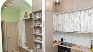 Eine Küche mit Holzsäcken, einer Marmor-Spritzschutzwand und einem schwarzen Herd.