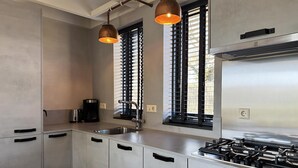 A modern kitchen with stainless steel appliances, a gas stove, and a coffee maker. - 1 bedroom accommodation in Callantsoog (Callantsoog)