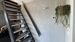 A modern staircase with a geometric design, a hanging plant, and a door with a smoke detector. - 1 bedroom accommodation in Callantsoog (Callantsoog)