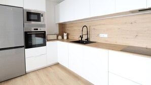Una cocina moderna con electrodomésticos de acero inoxidable, armarios blancos y un protector contra salpicaduras de madera.