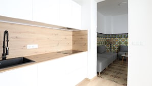 Una cocina moderna con armarios blancos, un lavamanos negro y un protector de salpicadero de madera.