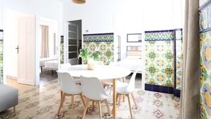 Una habitación moderna y bien iluminada con una mesa de comedor redonda, sillas blancas y una lámpara colgante.